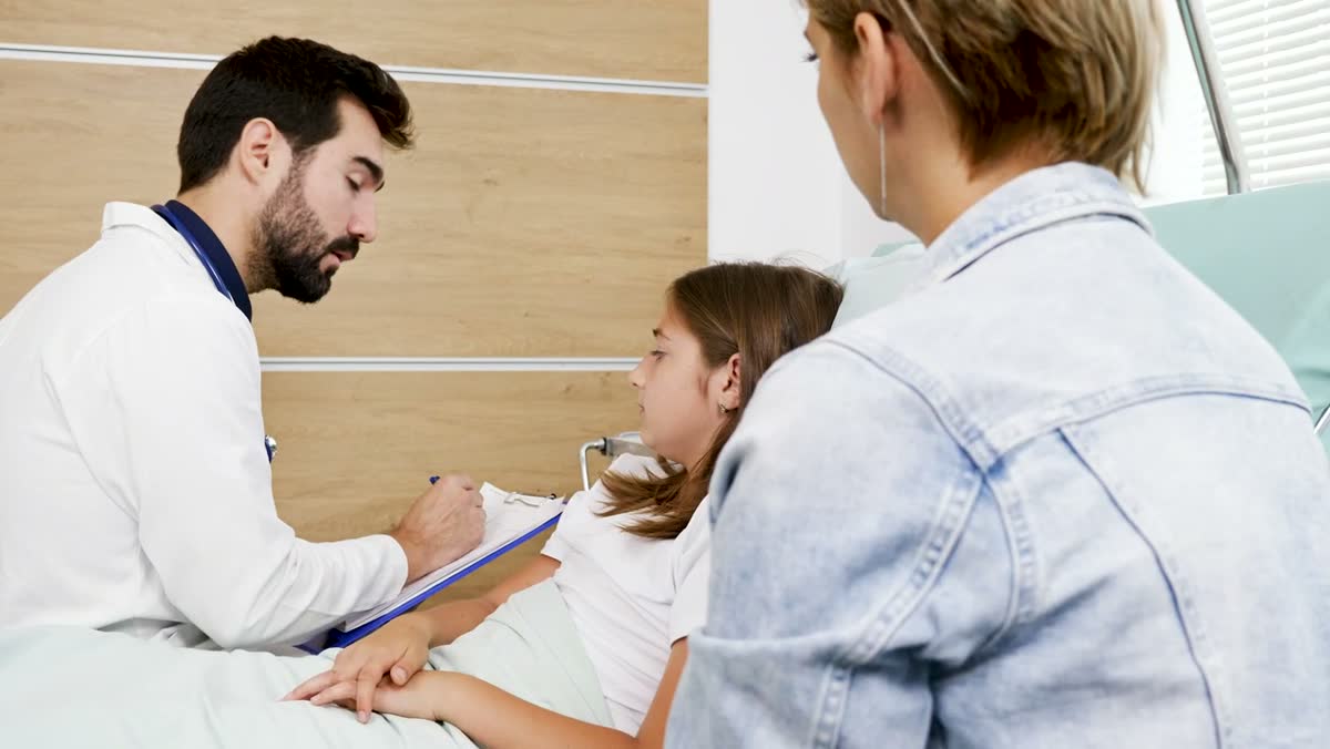 A doctor talking with a young patient and her mother